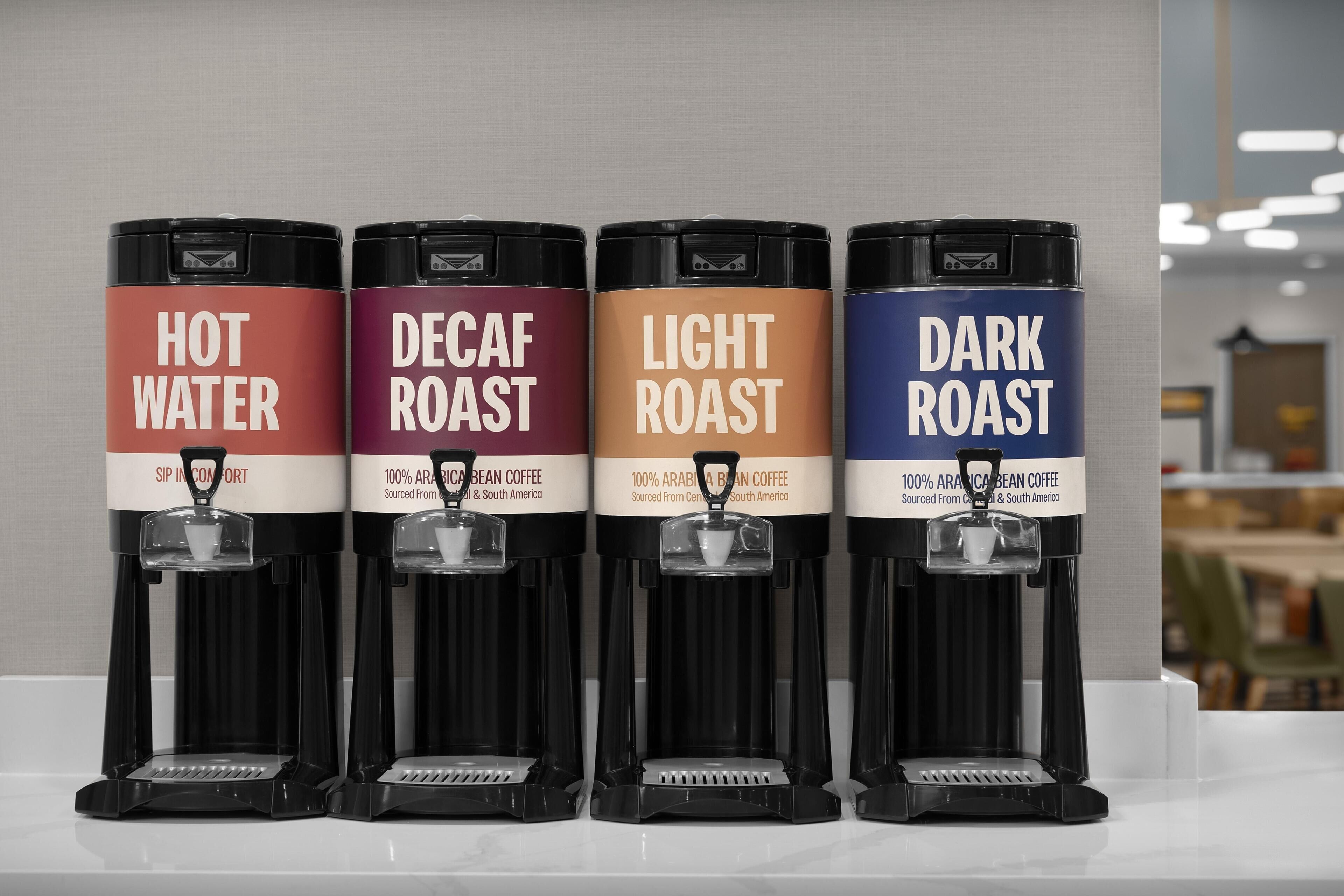 Four coffee dispensers labeled 'HOT WATER,' 'DECAF ROAST,' 'LIGHT ROAST,' and 'DARK ROAST,' each with a coffee cup on top.