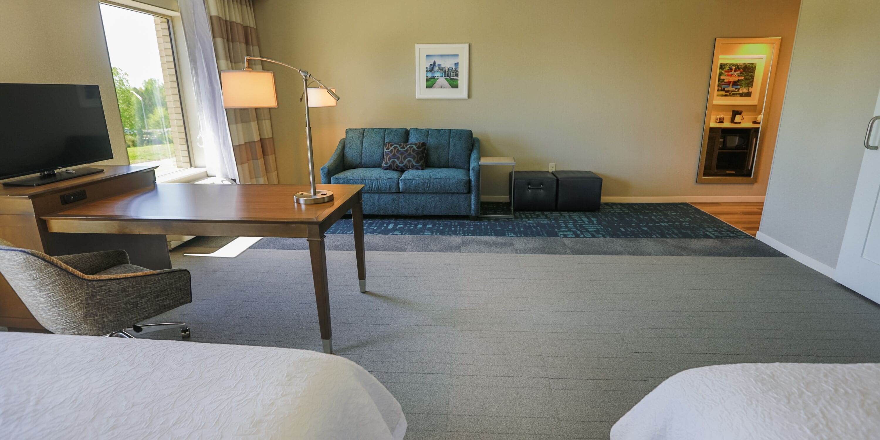 Une chambre d’hôtel équipée d’un lit, d’un bureau, d’une télévision, d’un canapé, d’une lampe et d’une petite armoire.