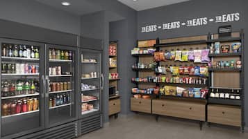 A grocery store interior with refrigerated beverage coolers, snack shelves, and a sign indicating a treats section.