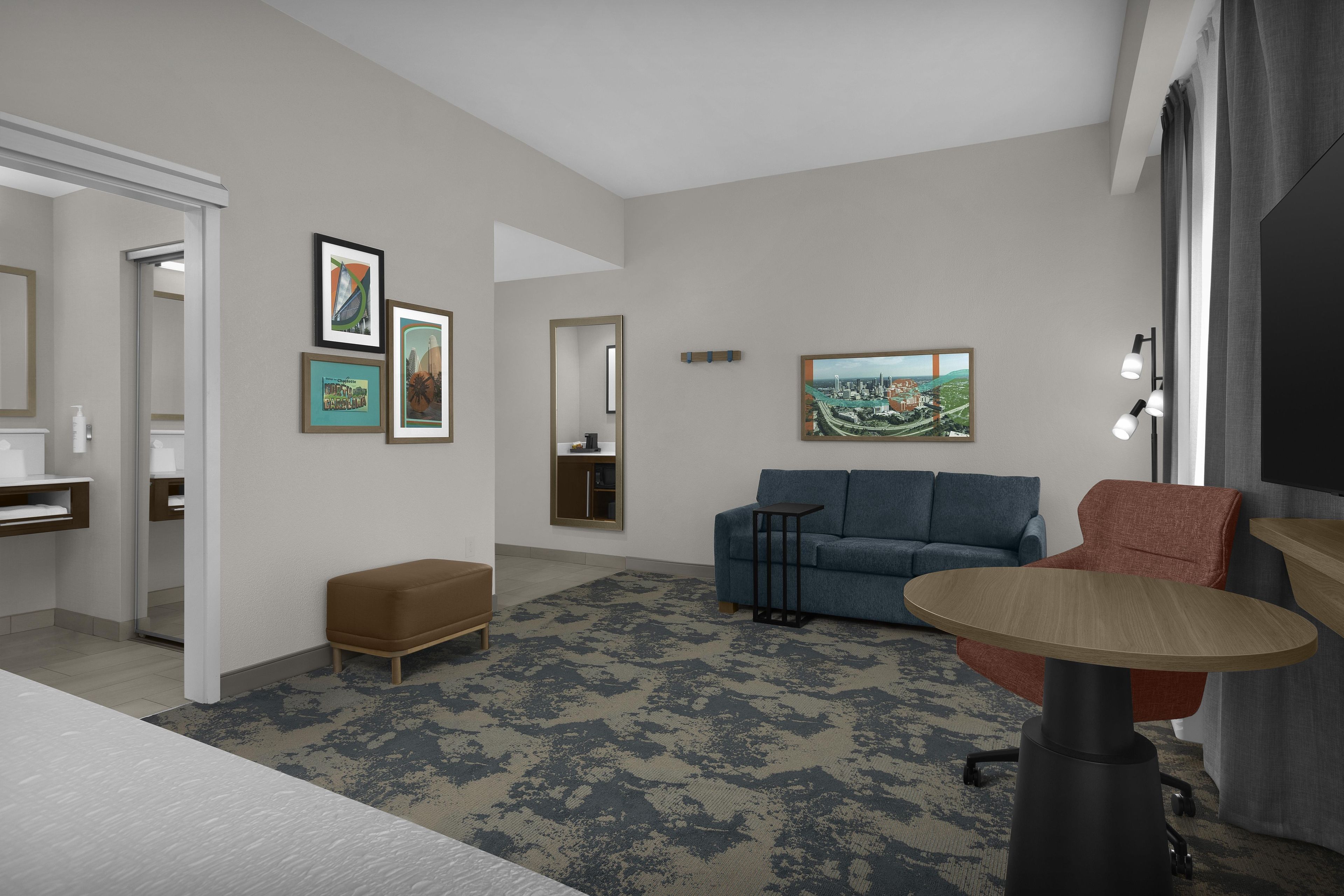 A modern living room with a sofa, a coffee table, and a TV. There are framed pictures on the wall and a small side table.
