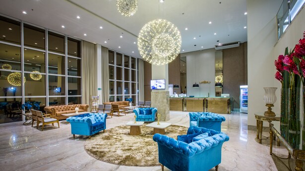 A spacious lobby with blue sofas, a marble floor, and large windows. - Céu Palmas Hotel (Palmas)