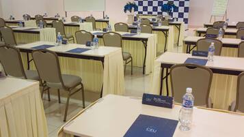 A conference room with multiple tables, chairs, nameplates, water bottles, and a whiteboard.