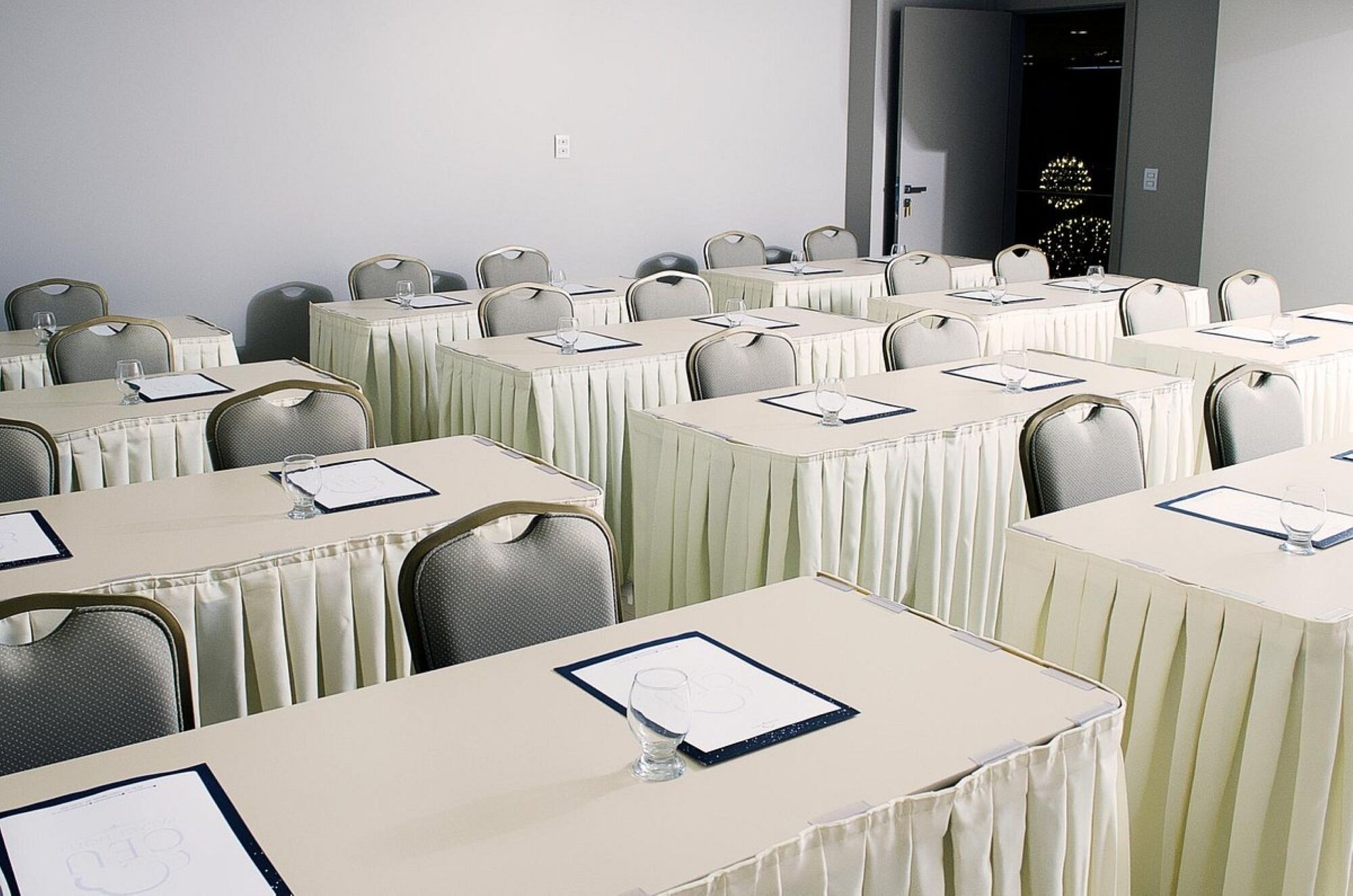 A conference room with multiple tables, each with a menu and a glass of water.