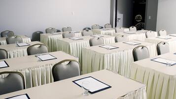 A conference room with multiple tables, each with a menu and a glass of water.