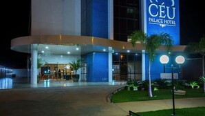 The exterior of the Cèu Palace Hotel with a prominent blue sign, a well-lit entrance, and a landscaped garden area. - Céu Palmas Hotel (Palmas)