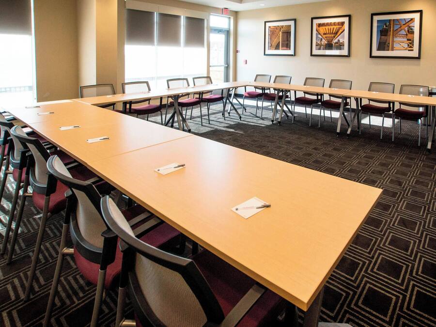 A conference room with a long table, multiple chairs, and framed pictures on the wall.