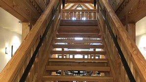A wooden staircase with a ceiling fan, leading to a room with a dining table and chairs.