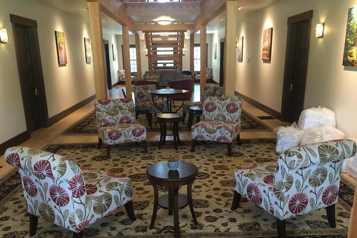 A hallway with patterned carpet, floral armchairs, and a central round table.