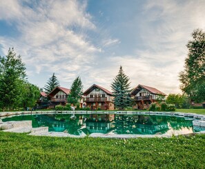 A resort with three wooden cabins, a central pool, and surrounding greenery. - Great Northern Resort (West Glacier)