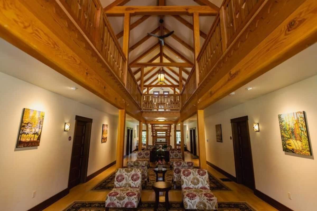 A hallway with wooden beams, a chandelier, and patterned chairs.