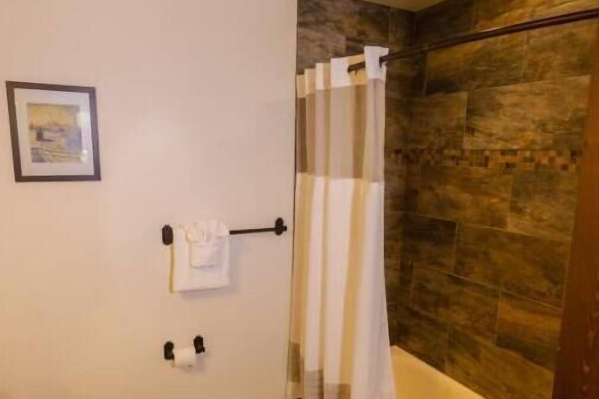 A bathroom with a toilet, a bathtub, a shower curtain, and a towel rack.