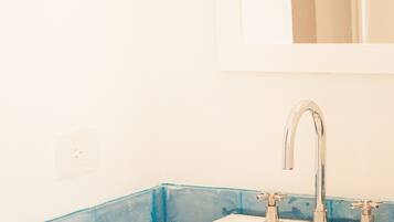 A bathroom with a white sink, a mirror above it, and a blue-tiled wall.
