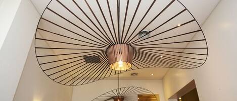 A modern interior with a large, fan-shaped ceiling light fixture and a smaller one below it.