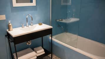 A bathroom with a white sink, a black vanity, a glass-enclosed shower, and a white bathtub.