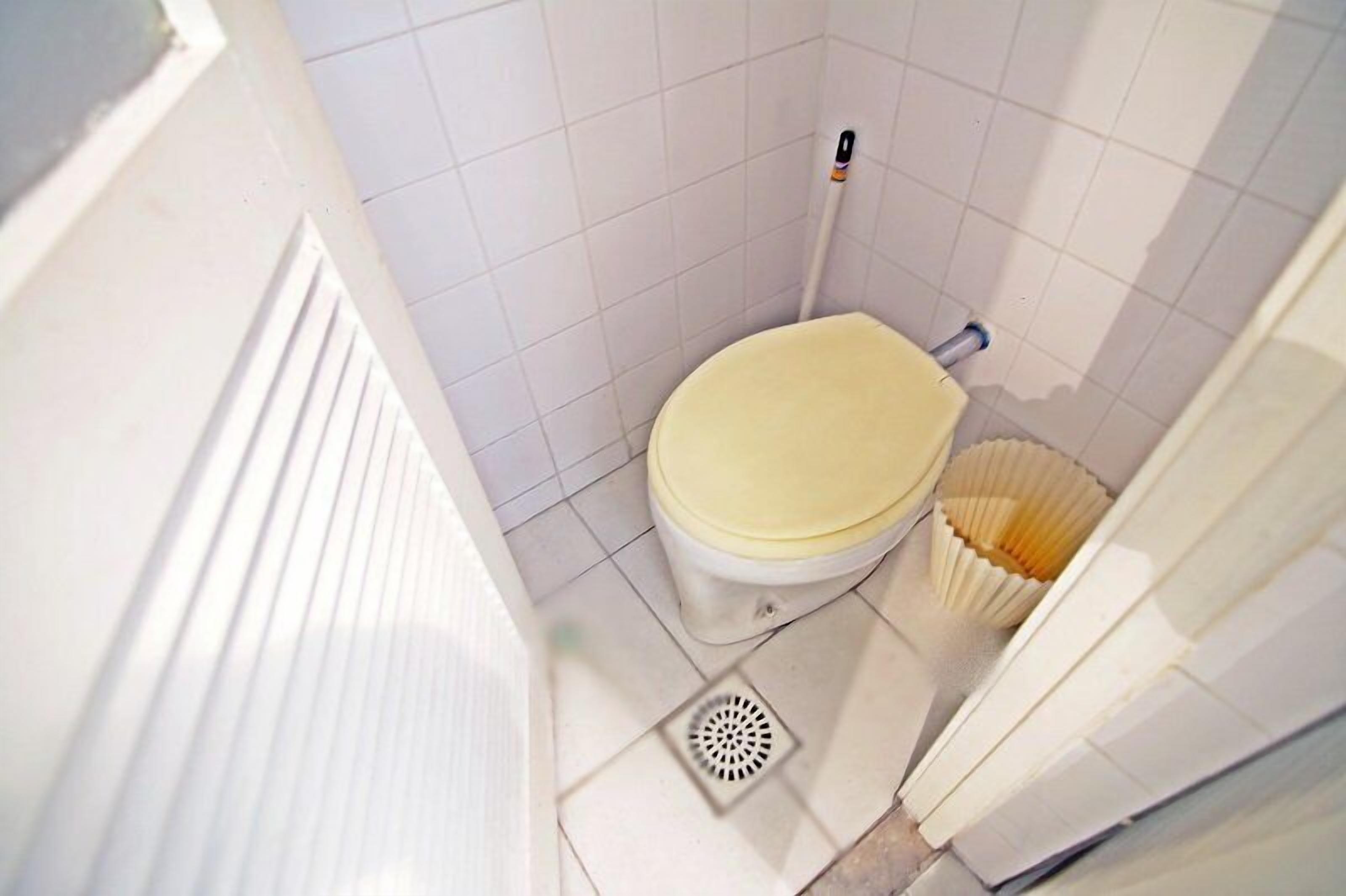 A small, compact bathroom with a toilet, a bidet, and a floor drain.