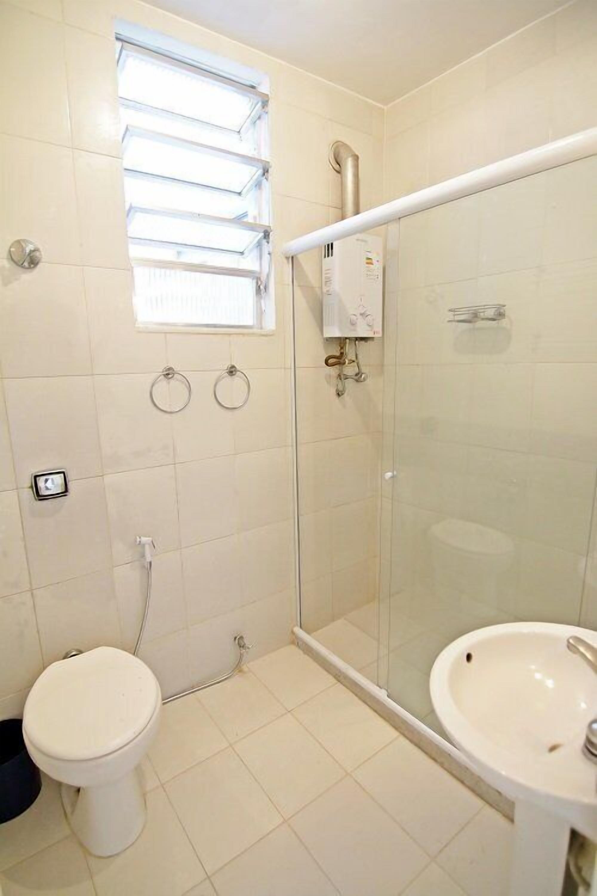 A bathroom with a glass-enclosed shower, a toilet, and a sink.