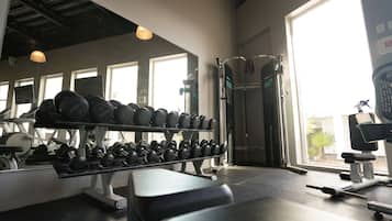 A gym with weightlifting equipment, mirrors, and large windows.