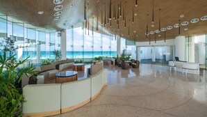 Un vestíbulo espacioso con una zona de estar curvada, ventanas amplias con vistas al océano y un diseño de techo moderno.