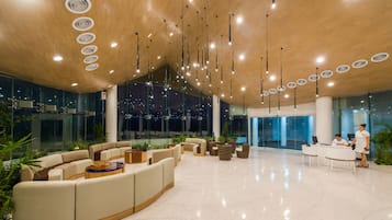 Un hall espacioso con una zona de estar curva, un mostrador de recepción y un diseño de techo moderno.