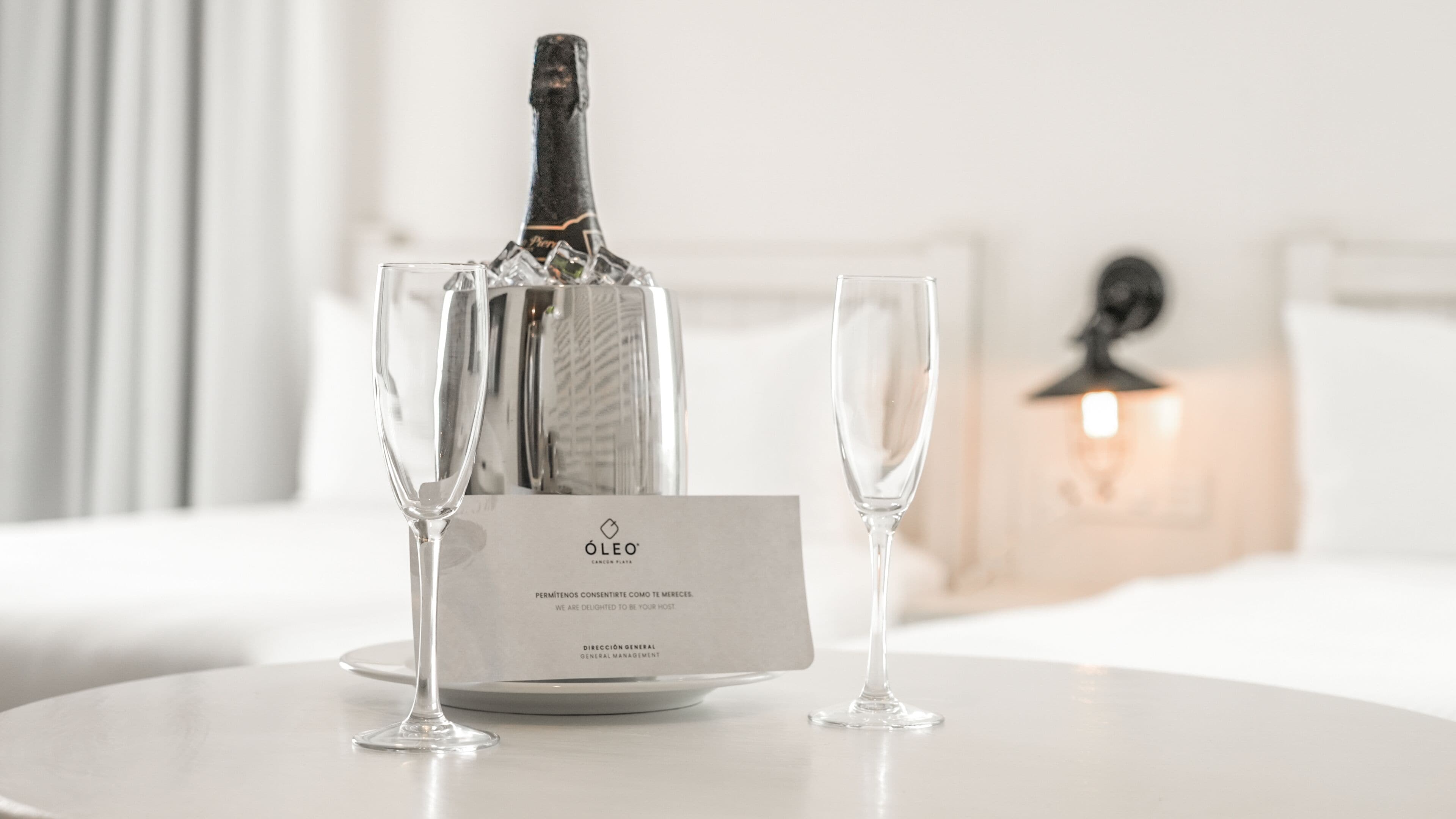 A bottle of champagne on a table with two glasses and a card.