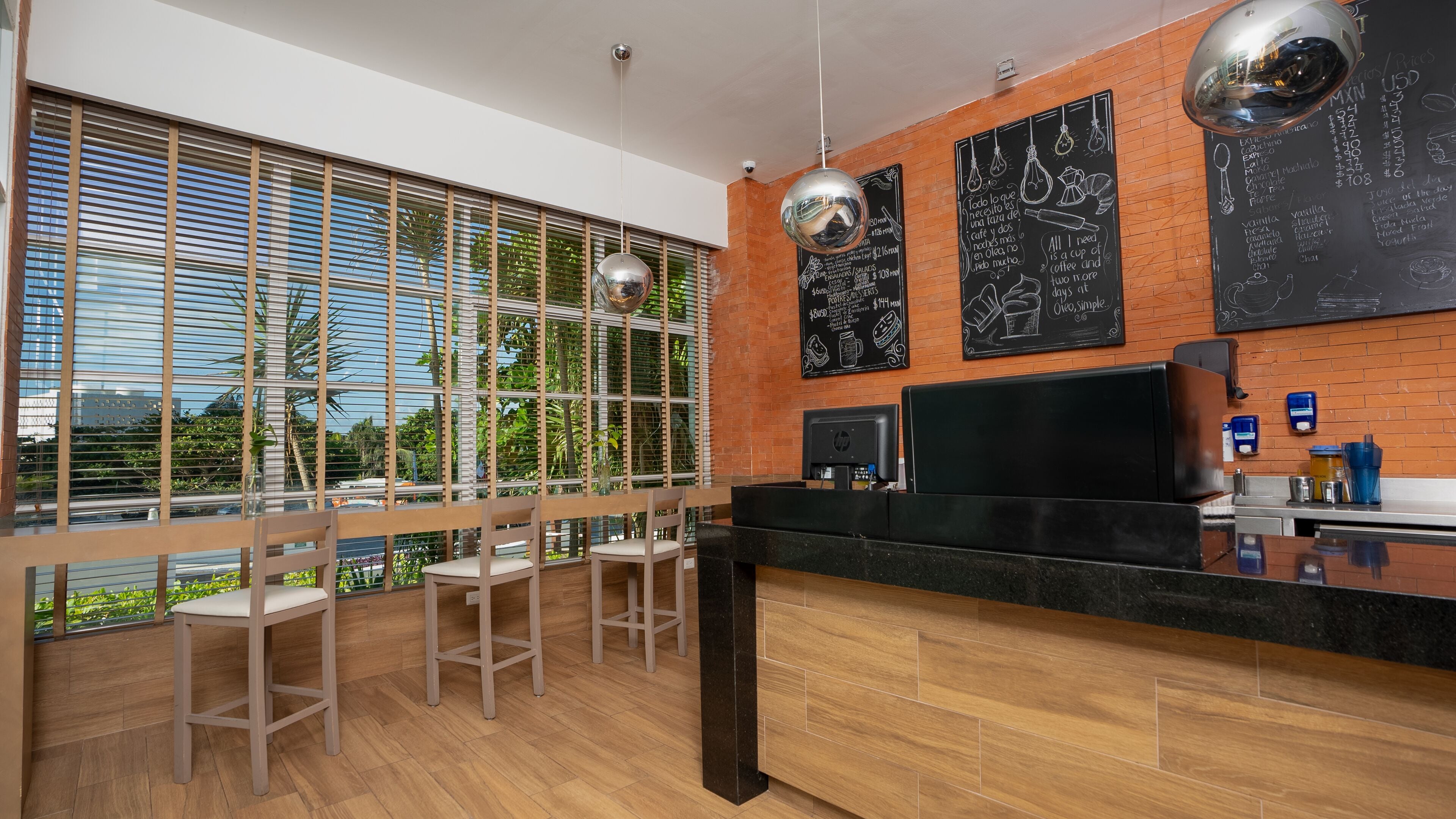 A modern kitchen with wooden flooring, a black countertop, and a large window with blinds.