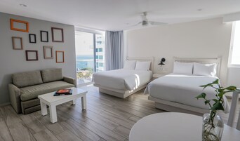 Una habitación de hotel con sofá, dos camas, una mesita de centro y vista al océano.