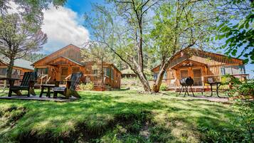 Alojamiento de estilo rústico tipo cabaña, con varias cabañas de madera, mobiliario exterior y un entorno natural.