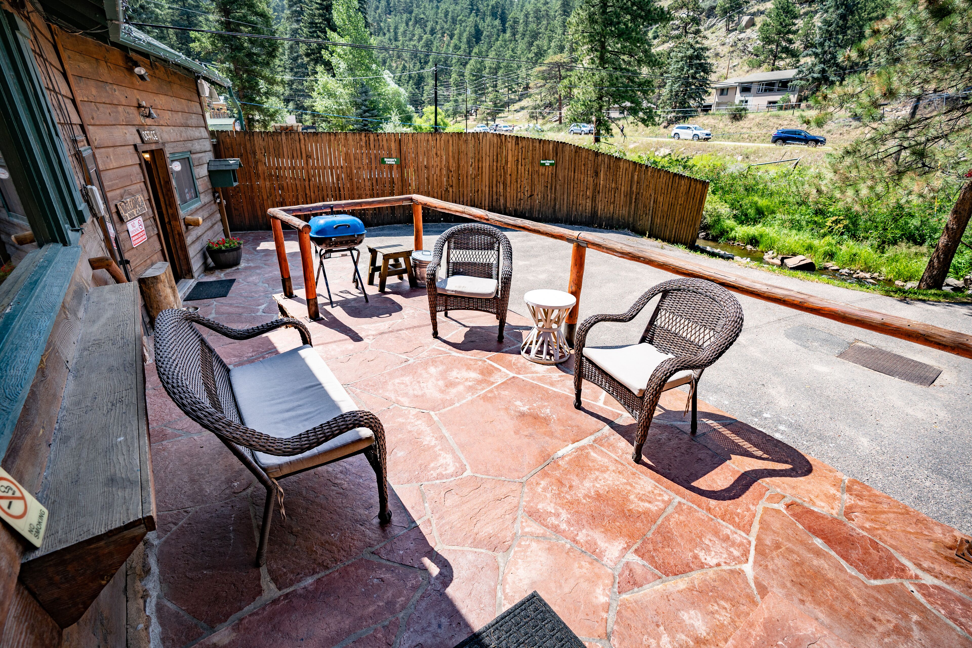 A patio with wicker furniture, a barbecue grill, and a stone floor.