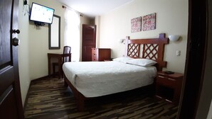 A bedroom with a bed, a desk, a chair, a wardrobe, and a television on the wall. - Pretty House Hostel (Lima)