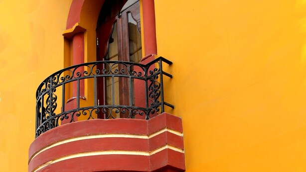 A building with a red balcony with ornate metal railings and a window. - Pretty House Hostel (Lima)