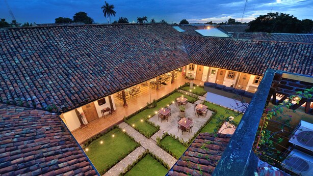 A courtyard with tiled roofs, outdoor seating, and a well-maintained lawn. - Hotel La Posada del Doctor (León)