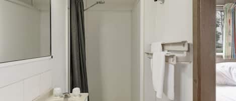 A bathroom with a shower, a mirror, a towel rack, and a sink.