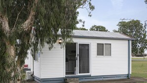 A small, single-story building with a metal roof, a sliding glass door, and a small porch area.