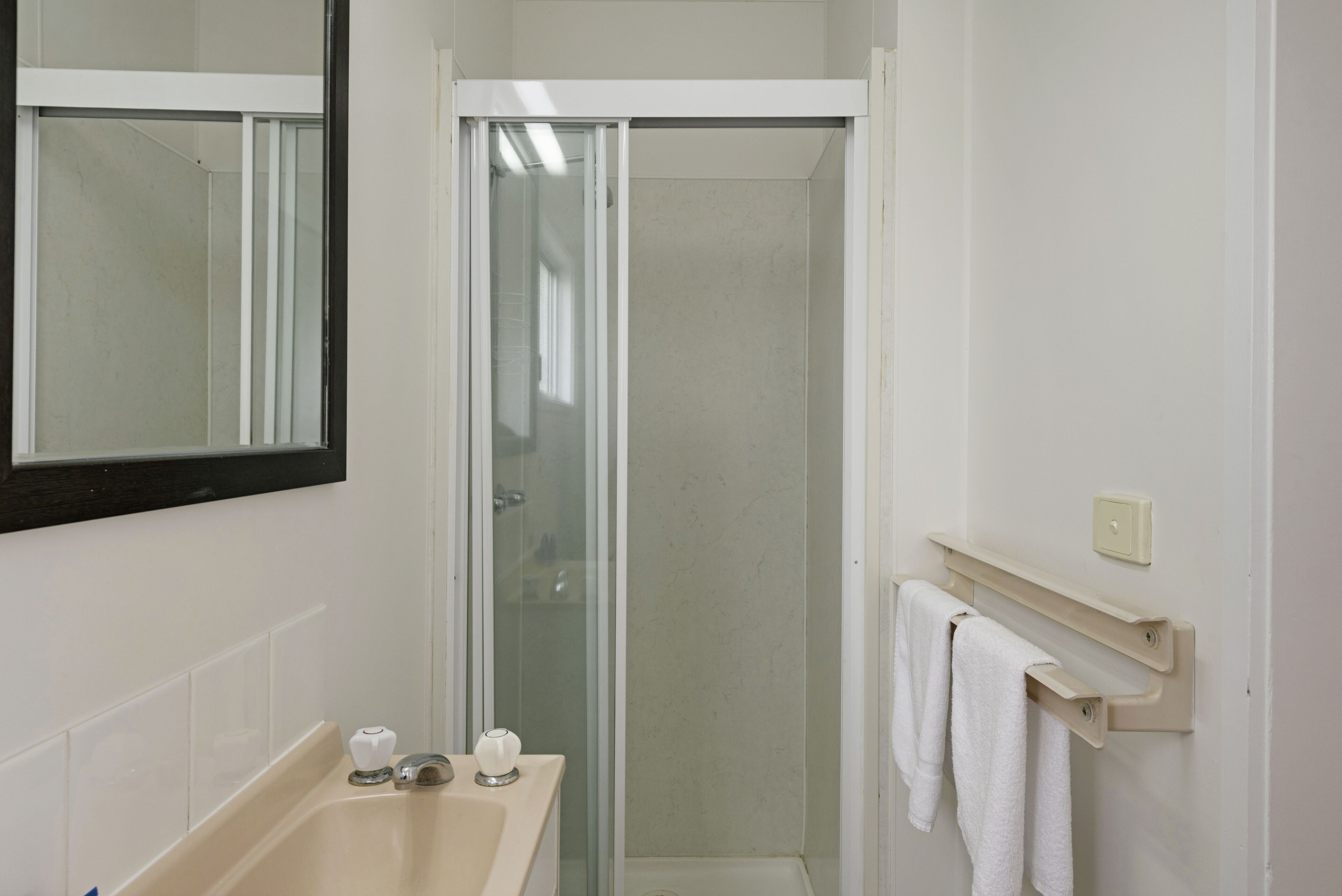 A bathroom with a bathtub, a glass-enclosed shower, and a towel rack.