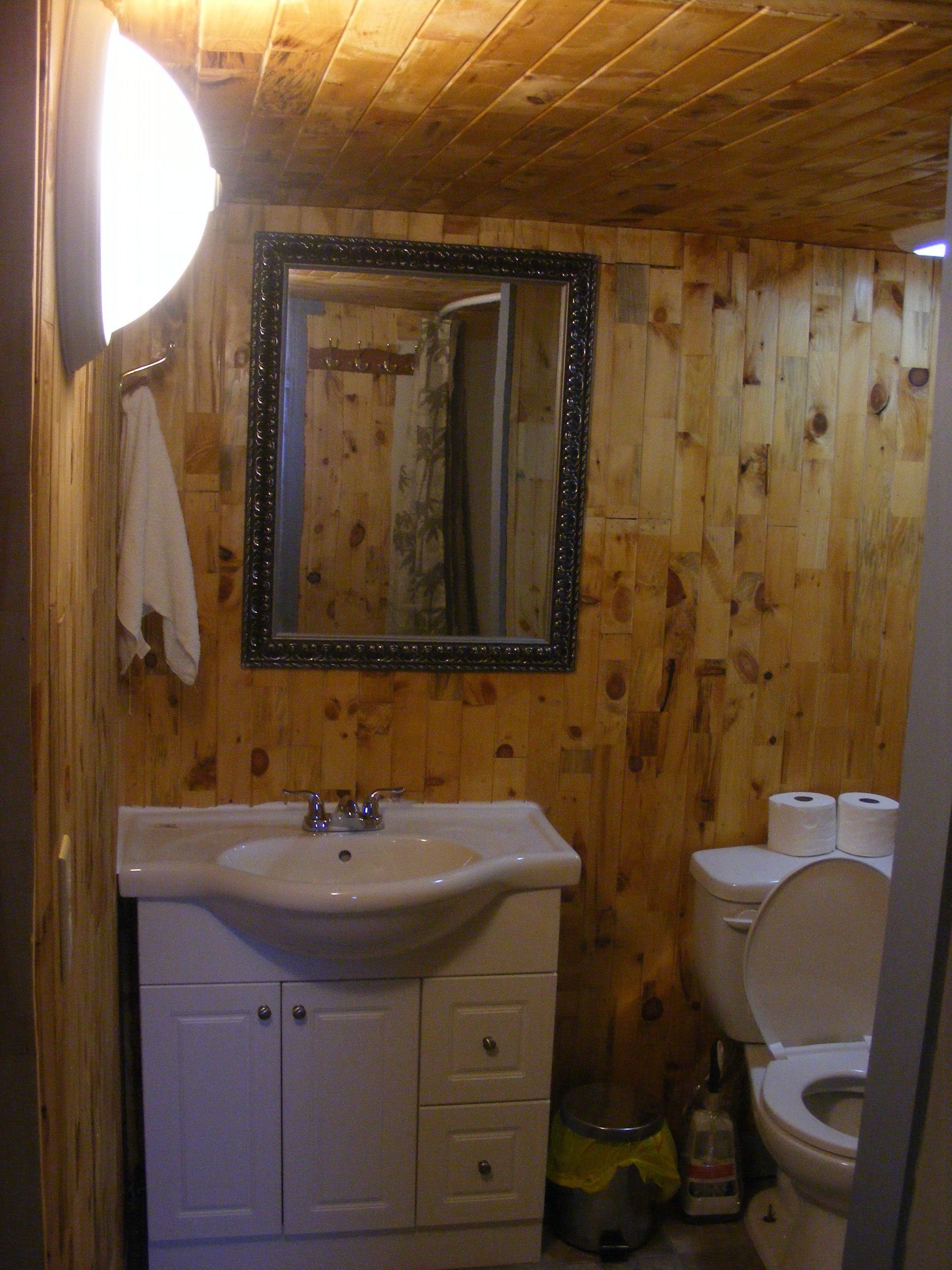 A wooden-paneled bathroom with a white sink, mirror, and toilet.