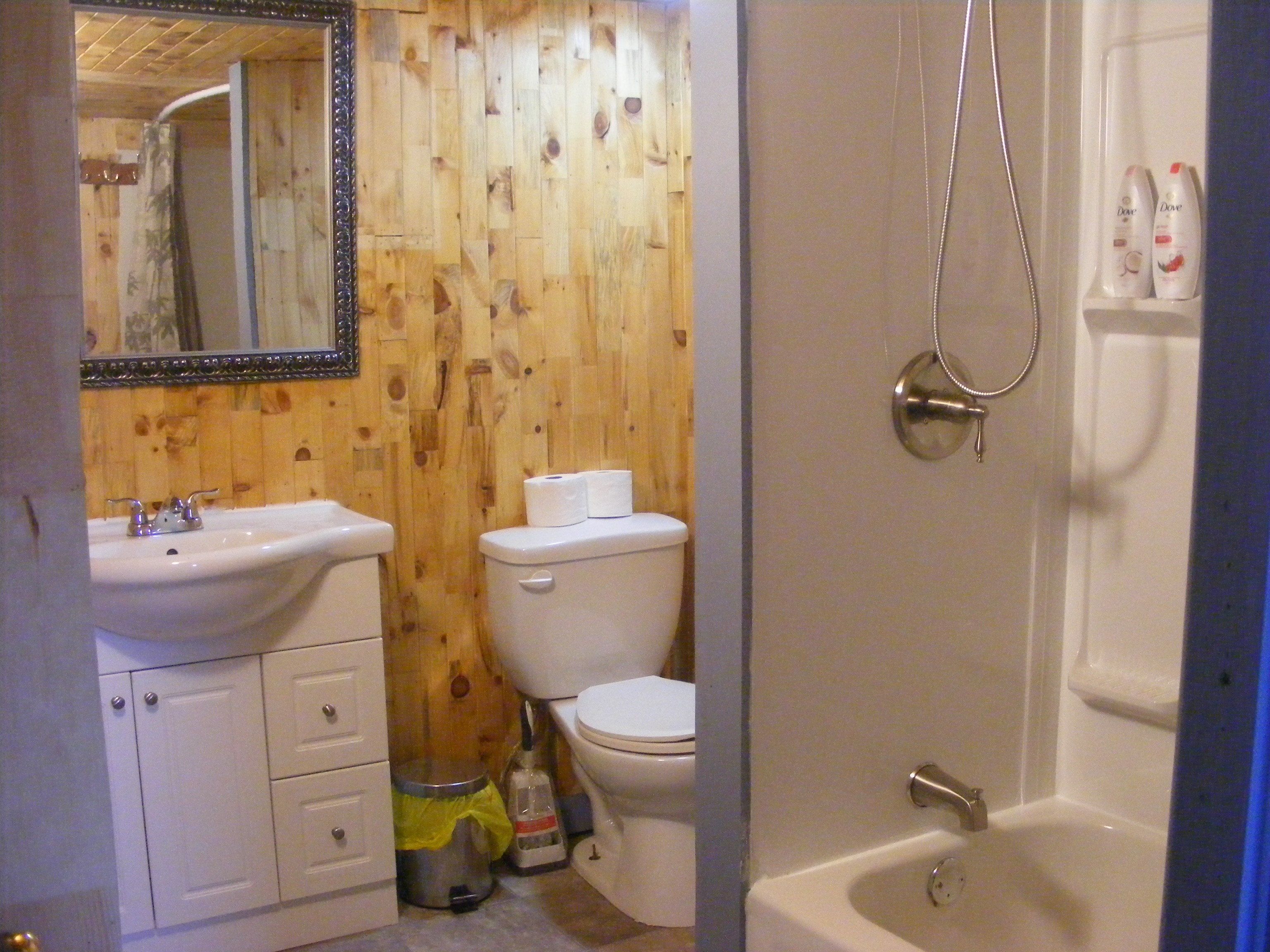 Ein Badezimmer mit Holzvertäfelung, einem weißen Waschbecken, einer Toilette und einer Badewanne.