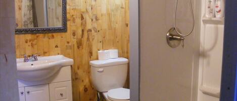 A bathroom with a wooden wall, a white sink, a toilet, and a bathtub.