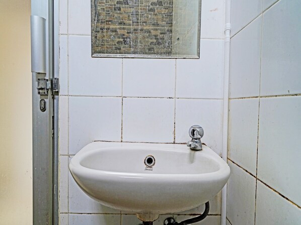 A bathroom with a white sink, a window above it, and a door with a metal handle. - OYO 1699 Verona Residence (Bandung)