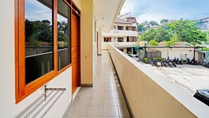 Un largo pasillo con vista a un estacionamiento y edificios al fondo.