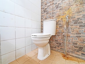 A bathroom with a toilet, a shower, and a tiled floor. - OYO 1699 Verona Residence (Bandung)
