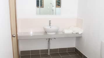 A small bathroom with a white sink, a mirror above it, a toilet, and a door.
