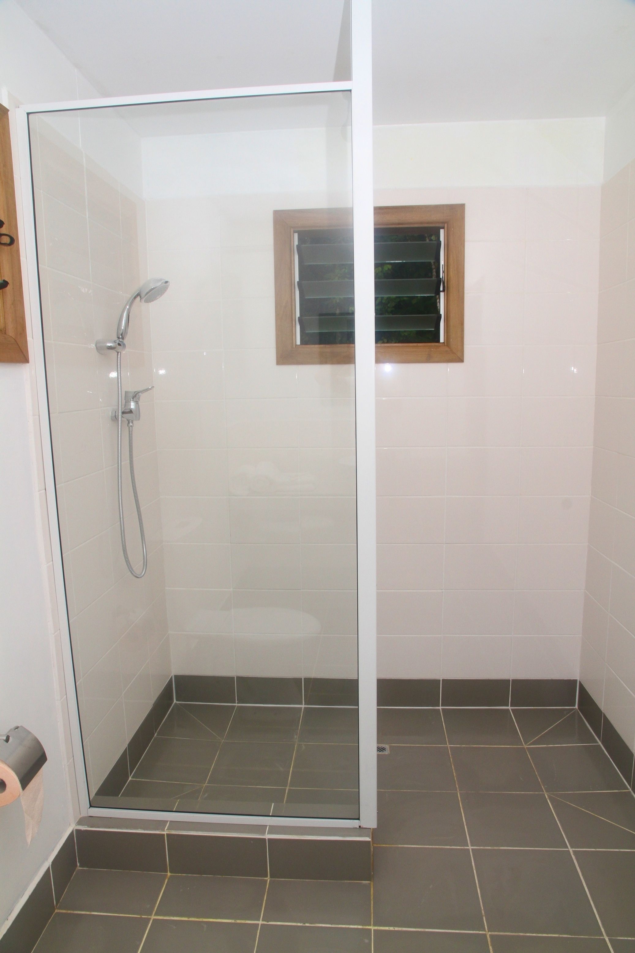 A glass-enclosed shower area with a showerhead and a small window.