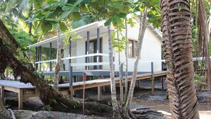 Una casa moderna con terraza de madera, rodeada de árboles y un gran tronco.