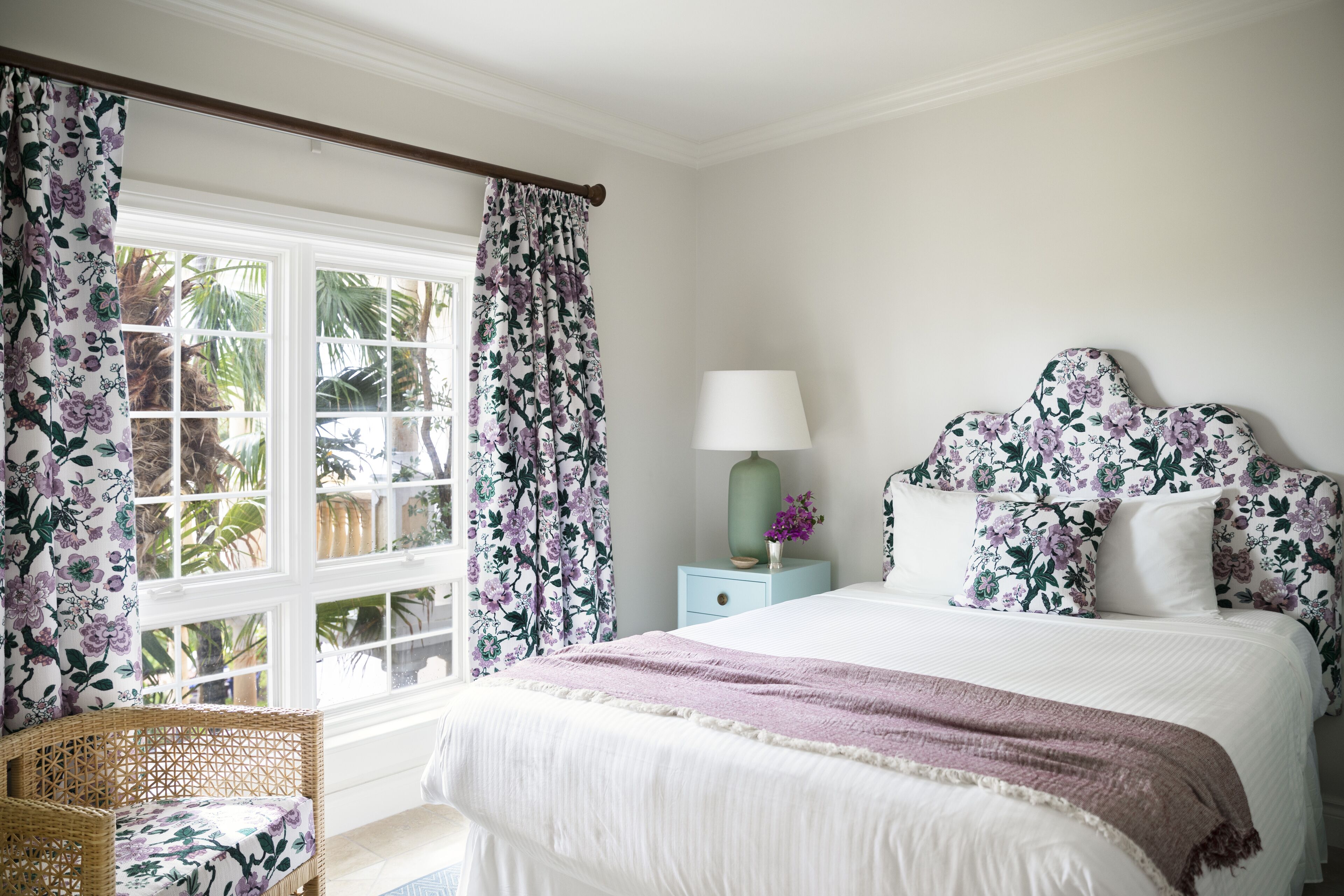 A bedroom with a bed, a nightstand, a lamp, and a chair.