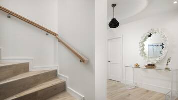 A staircase with wooden steps and a wooden handrail, leading to a white door.