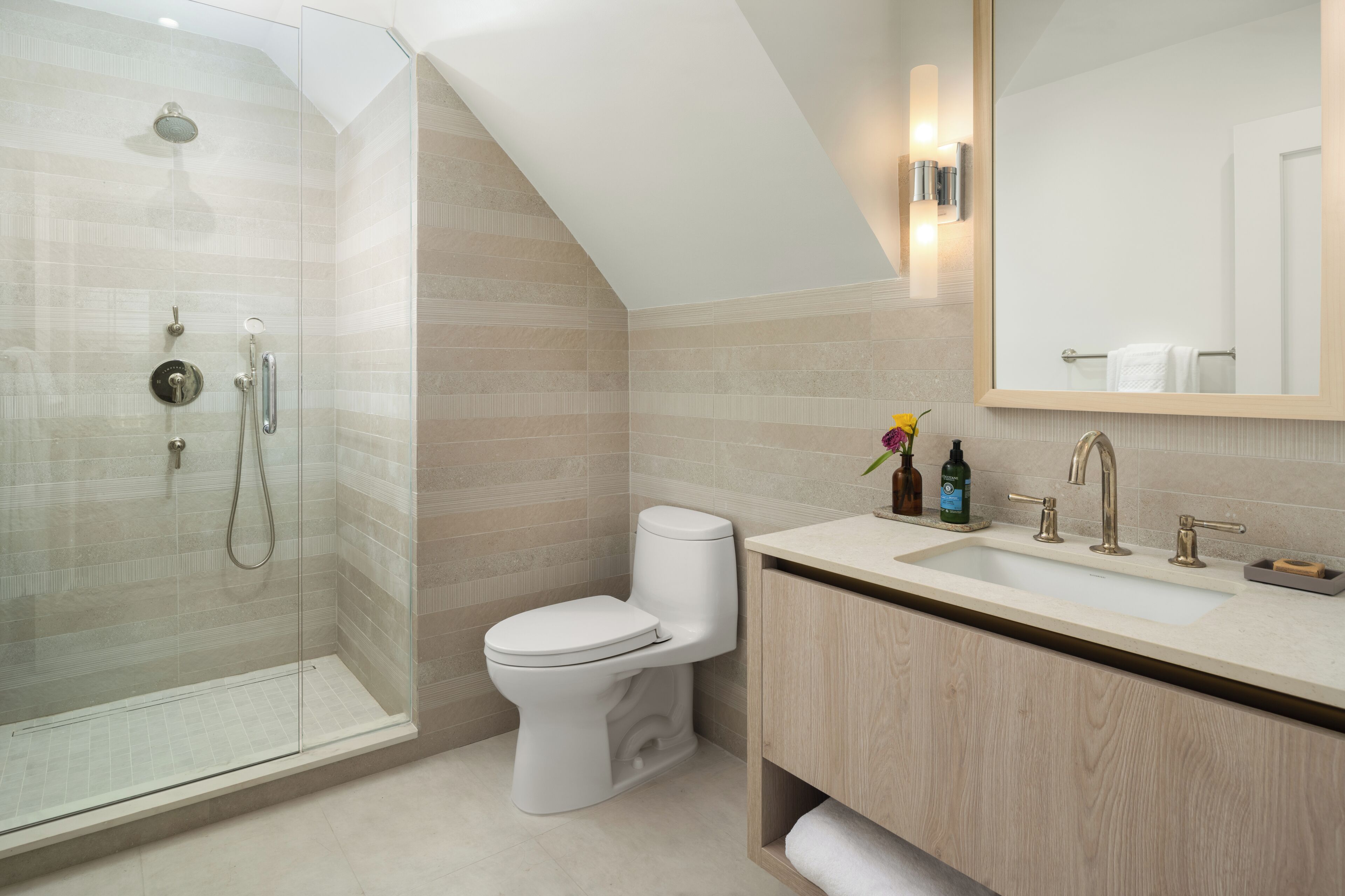 Une salle de bain moderne avec une douche à parois de verre, des toilettes et un meuble-lavabo avec un évier et un miroir.