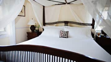 Una cama con dosel, una mesita de noche con lámpara y un atril con un florero.