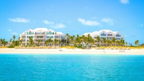 A beachfront hotel with multiple white buildings, palm trees, and a sandy beach.