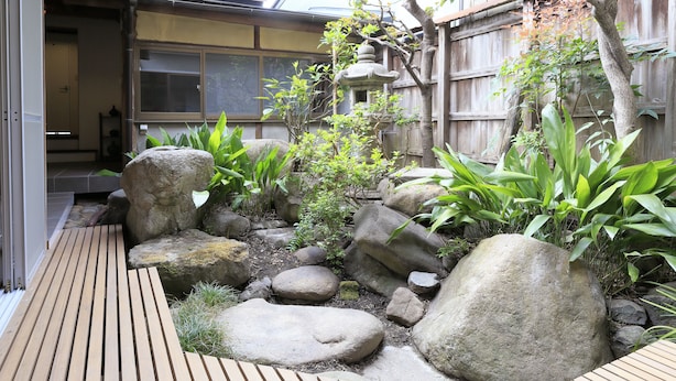 A garden with wooden decking, large rocks, and various plants. - NARA Guesthouse KAMUNABI - Hostel (Nara)
