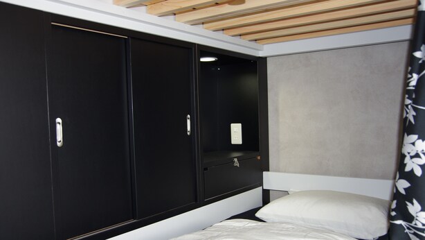 A bedroom with a bed, a wardrobe, and a headboard.